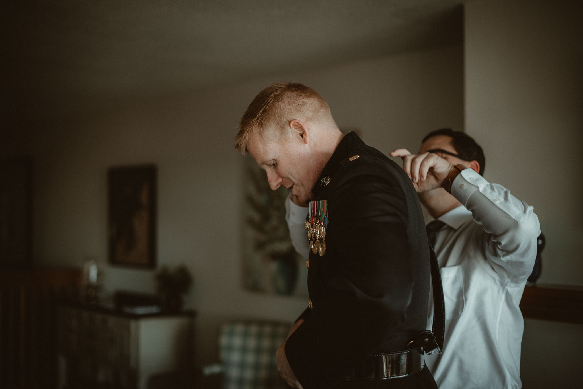 Best man helping the groom with his dress blues suit.