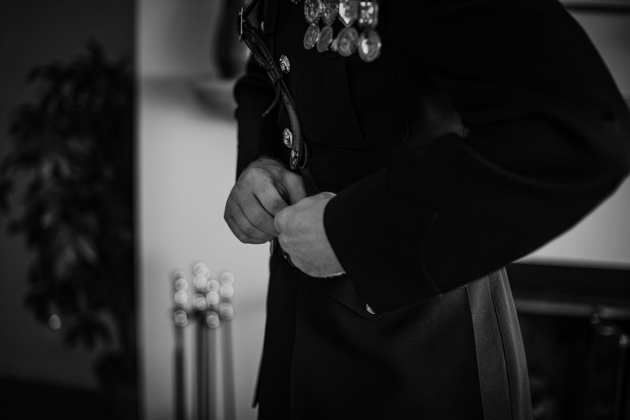 Black and white of groom buttoning his suit coat.