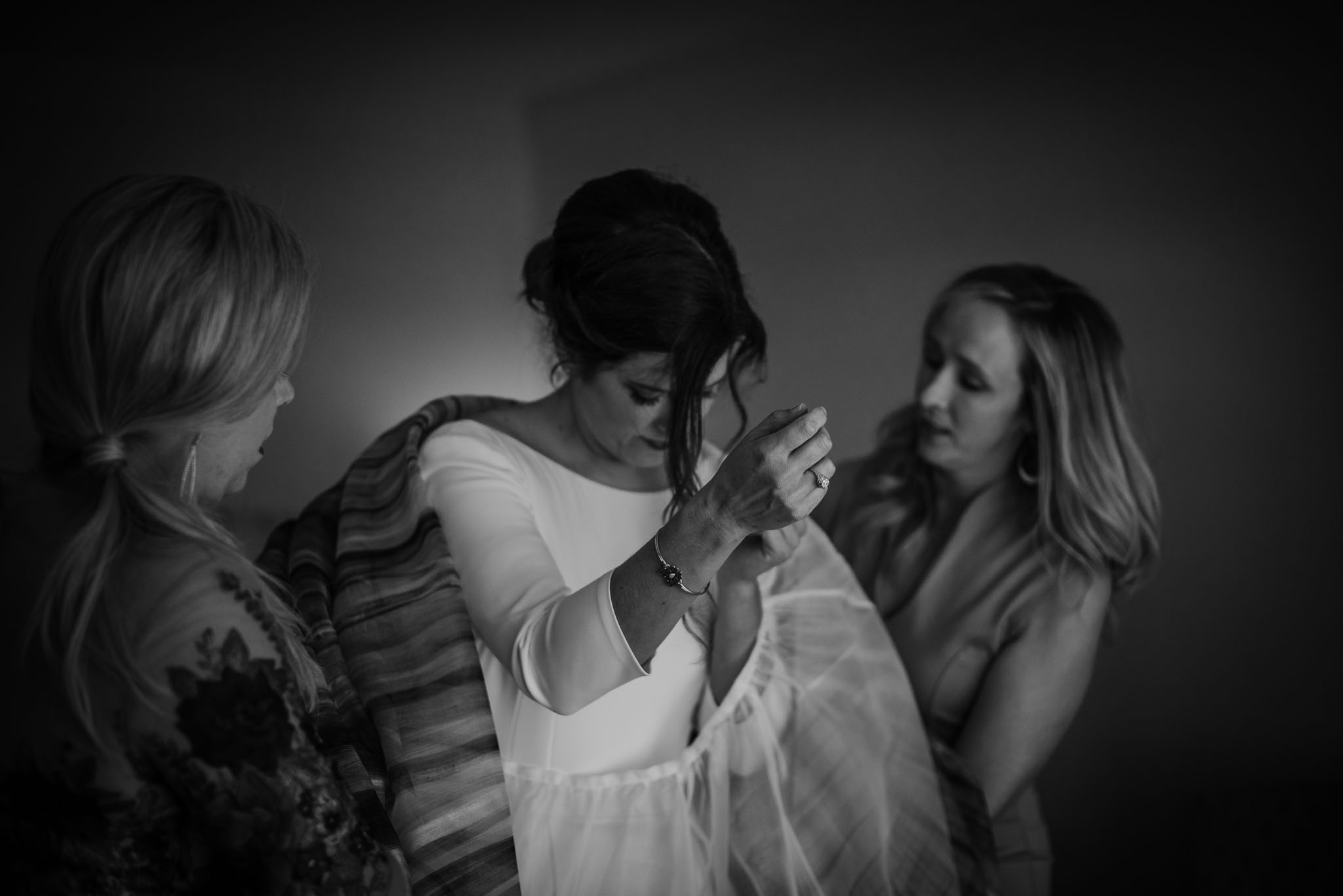 Bride's girlfriends helping her into her wedding dress.