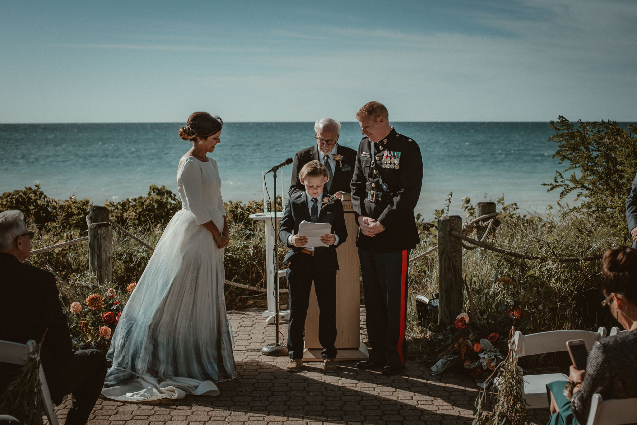The groom's son standing between the couple as he reads a special message to his dad and future step mom. 