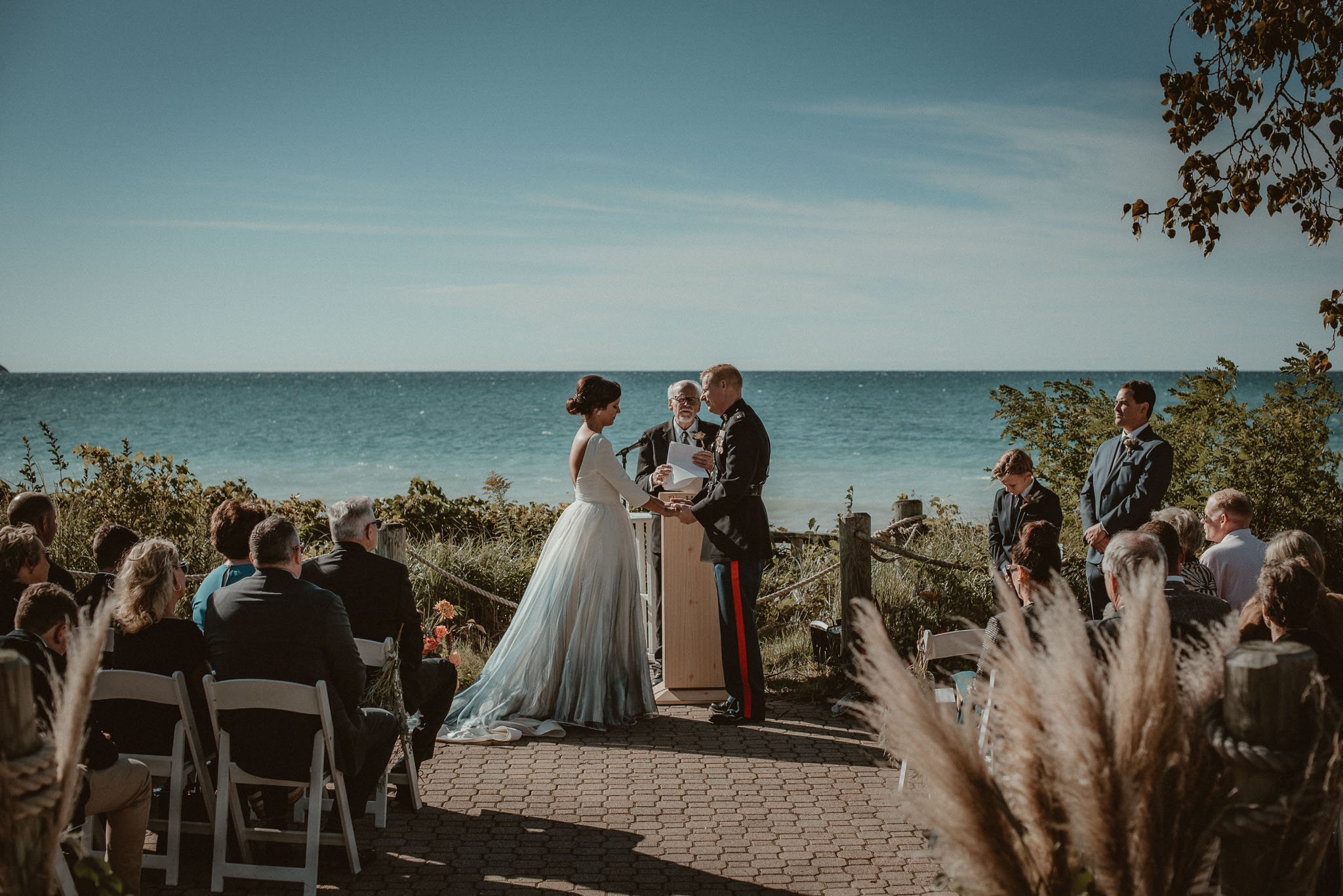 The bride and groom at the alter holding hands during the ceremony with Lake Michigan as a backdrop.