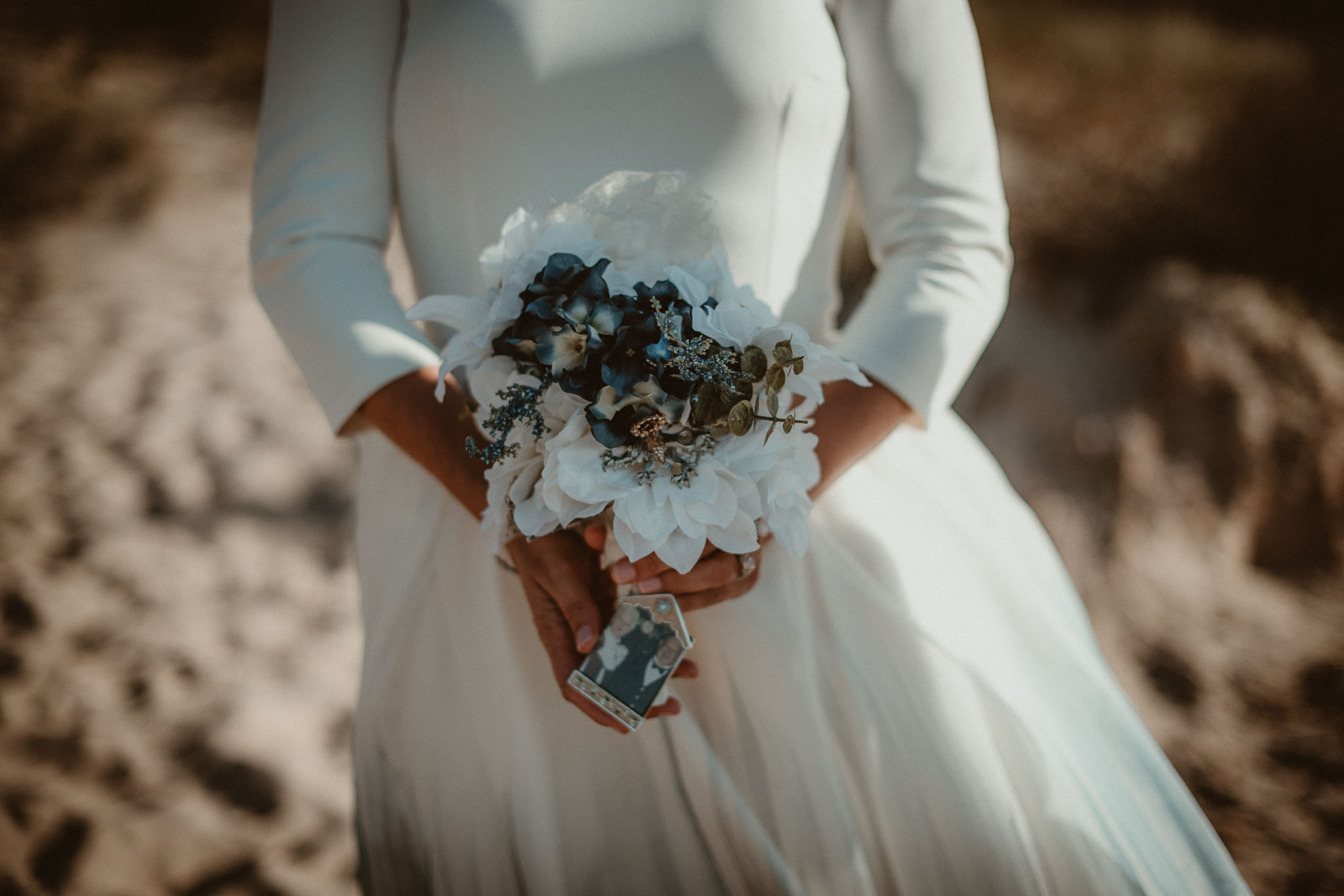 Bridal bouquet held in brides hands with photo of her late grandparents attached.   