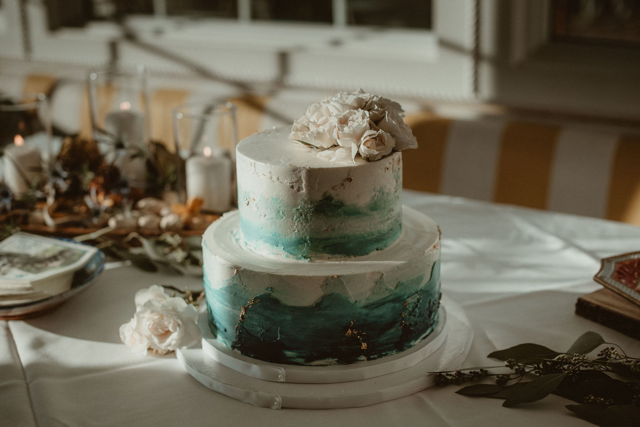 Small two tier wedding cake with fading Marine blue and flowers on top.