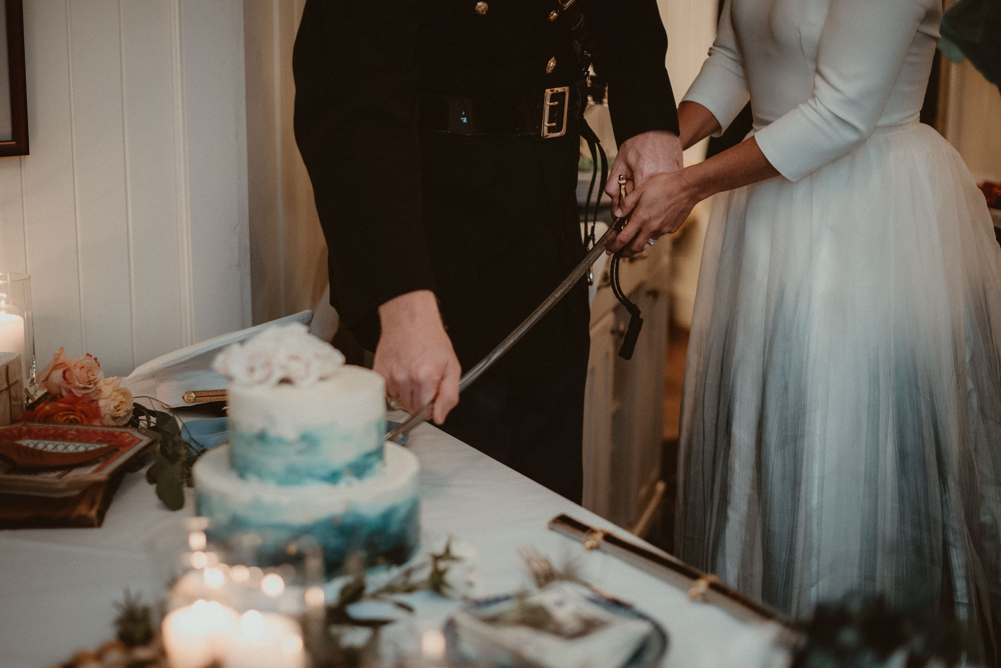 The couple cutting the wedding cake with the grooms sword.