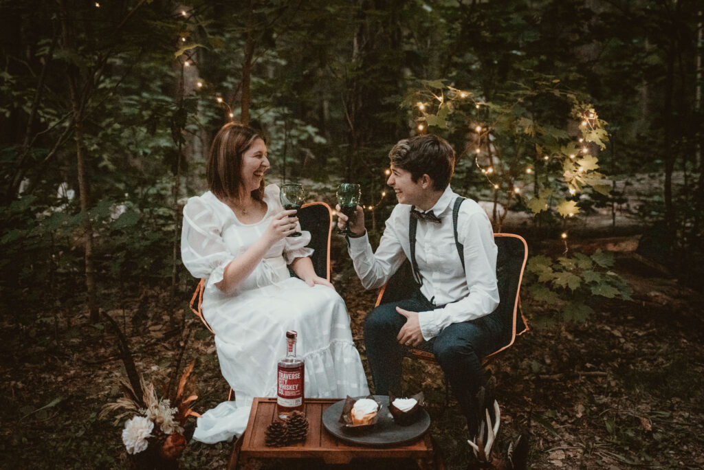 A couple toasting to their elopement in the woods at Hartwick Pines.