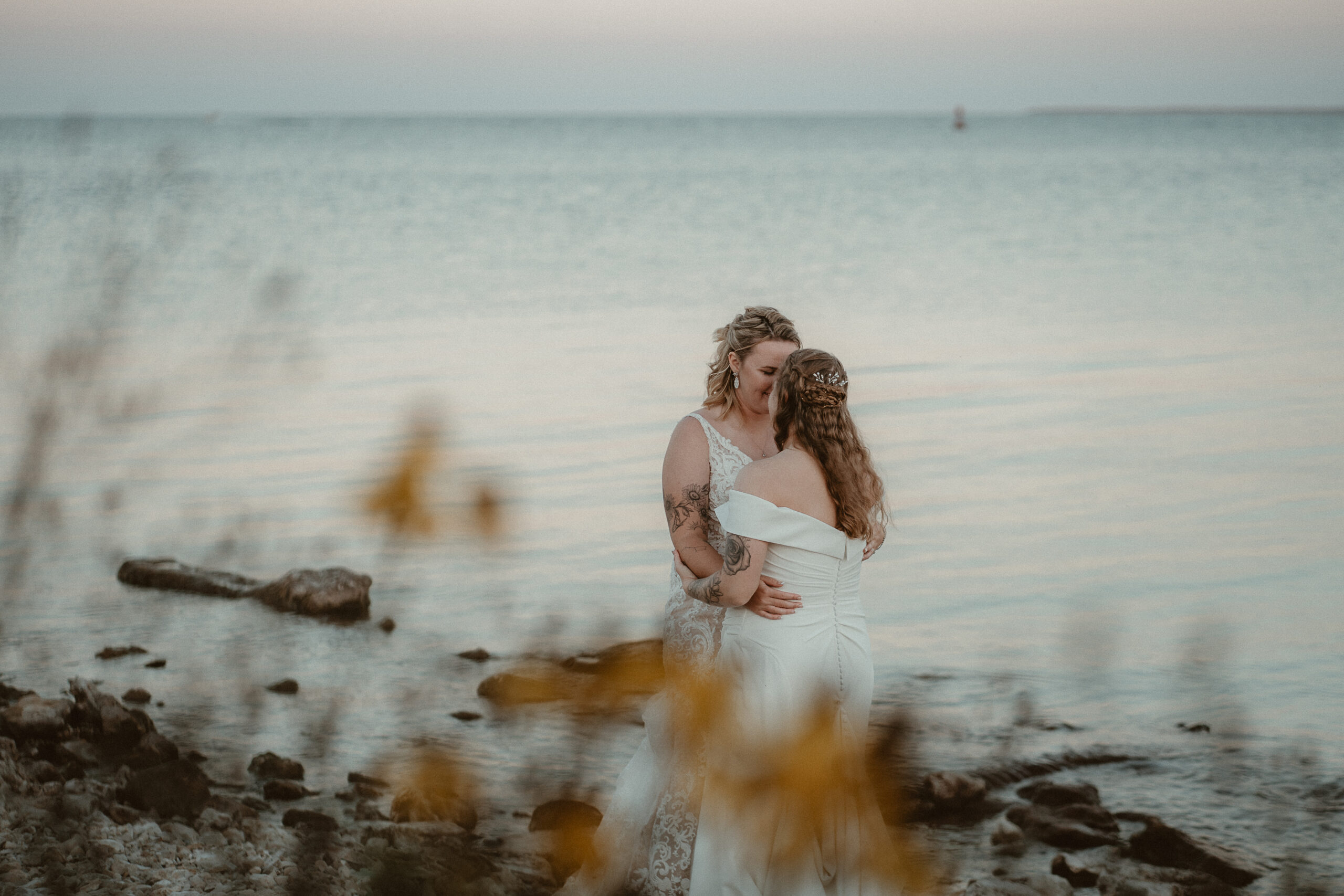 Brides hugging on the beach of Lake Huron at sunset