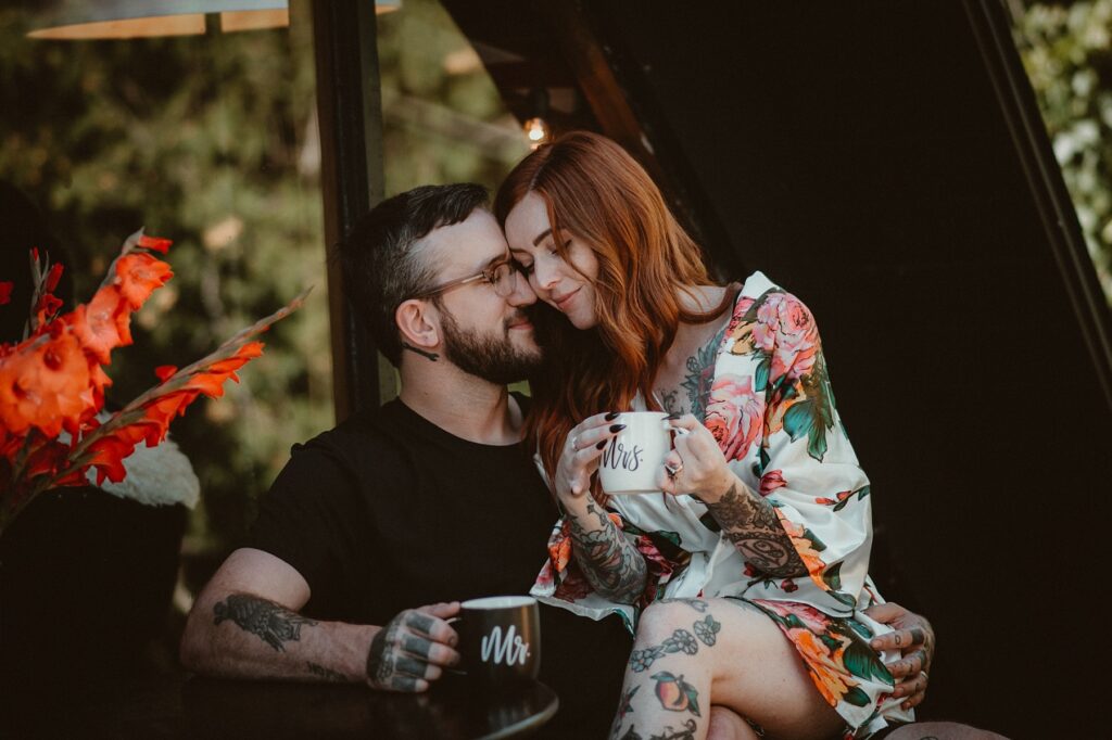 Couple having a relaxed elopement morning sitting outside in Northern Michigan sipping coffee.