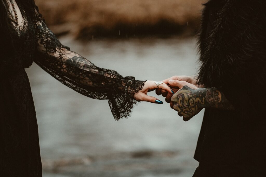 A close up of him holding her hand gently. She has long blue fingernails.
