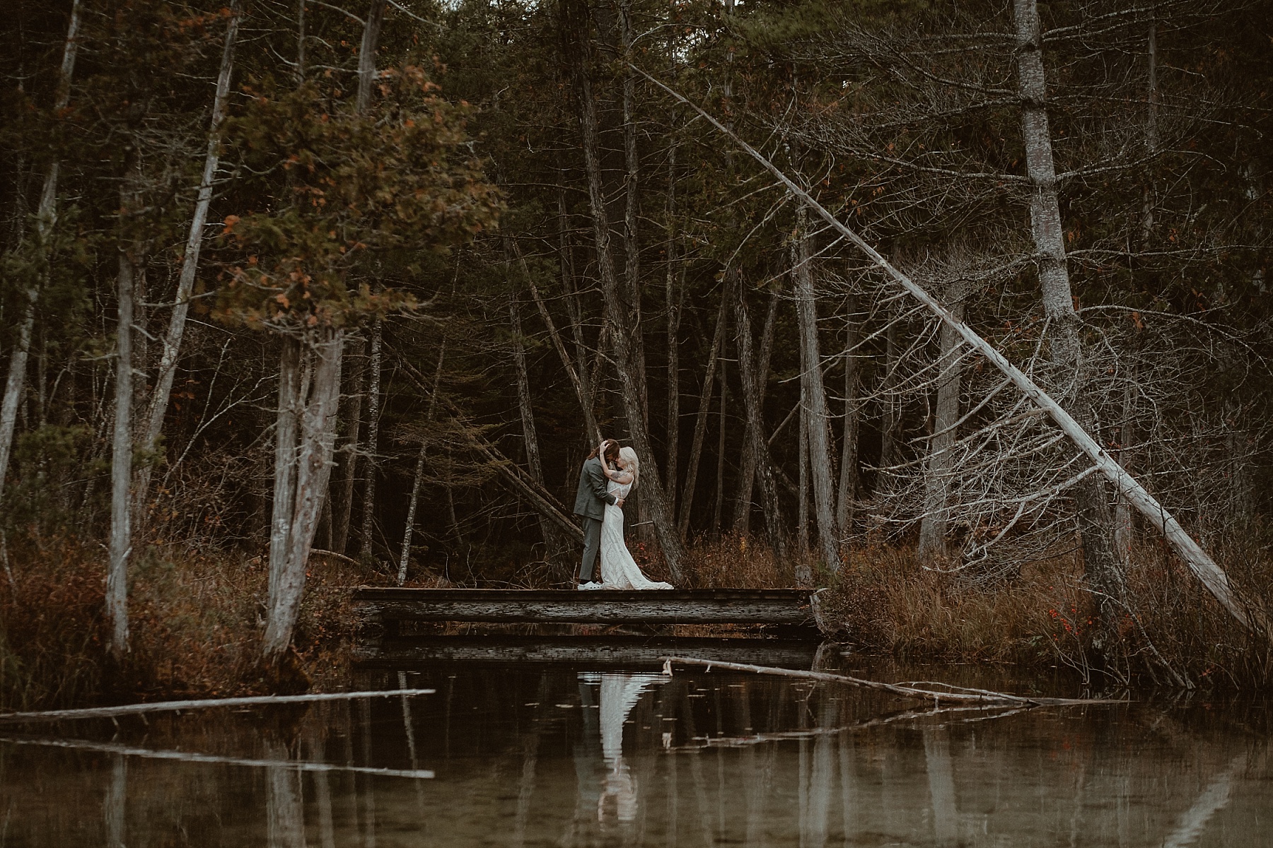 Groom and Bride holding each other on a small bridge