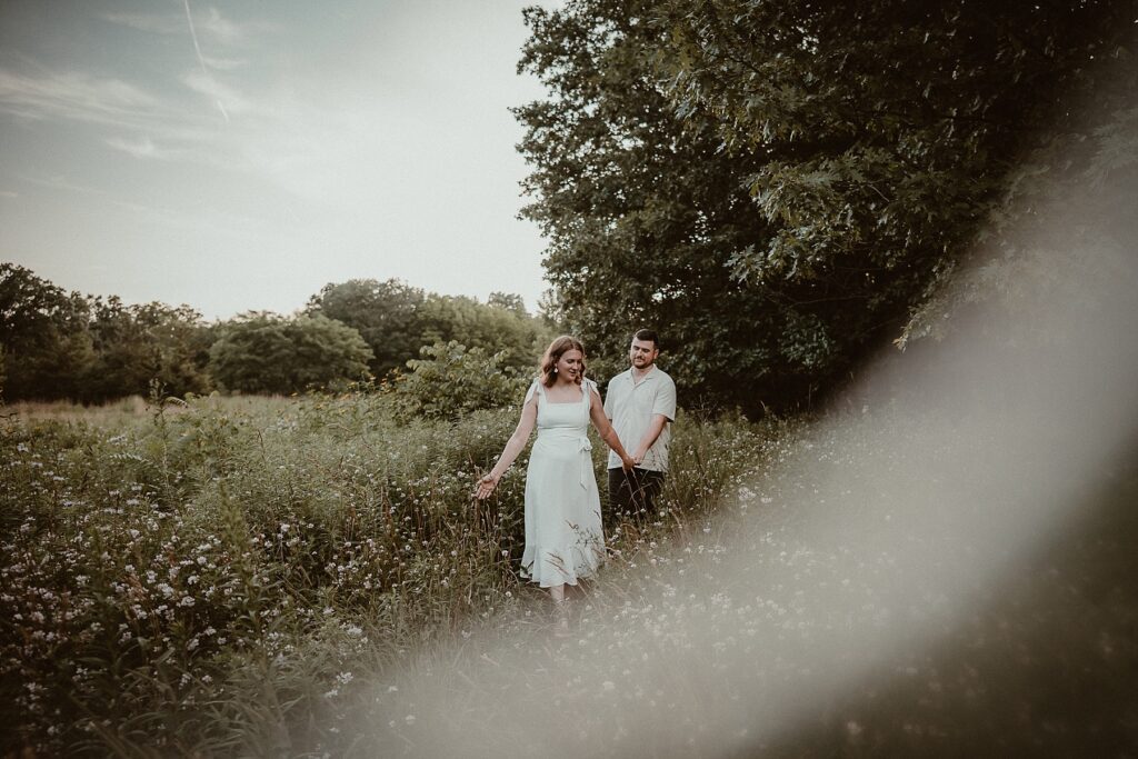 Couple walking through a field of wildflowers.