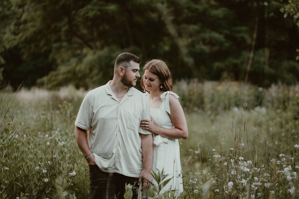 Couple standing together in a field of wild flowers.