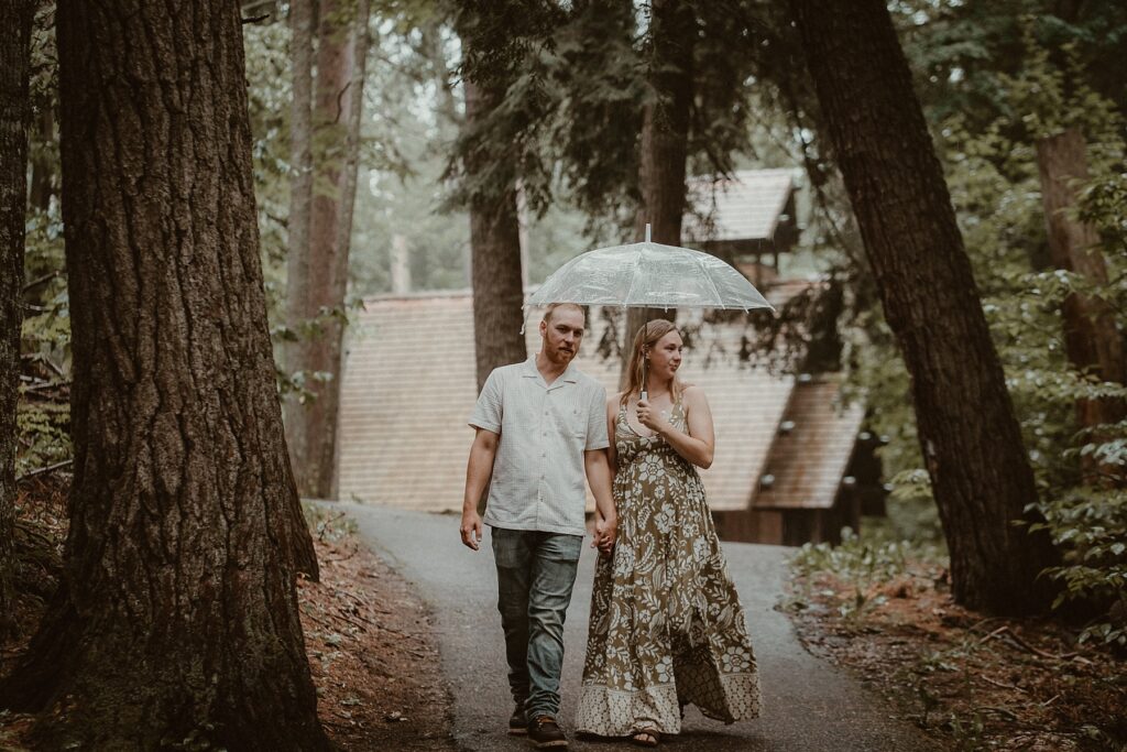 Couple walking in the rain, sharing an umbrella on a pathway.