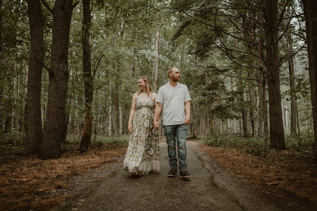 Couple walking together while holding hands along a path in the park.