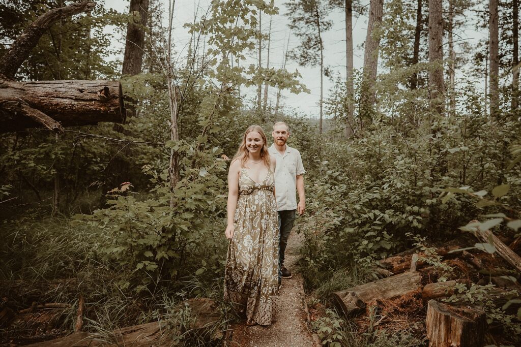 Couple walking down a path in the woods.