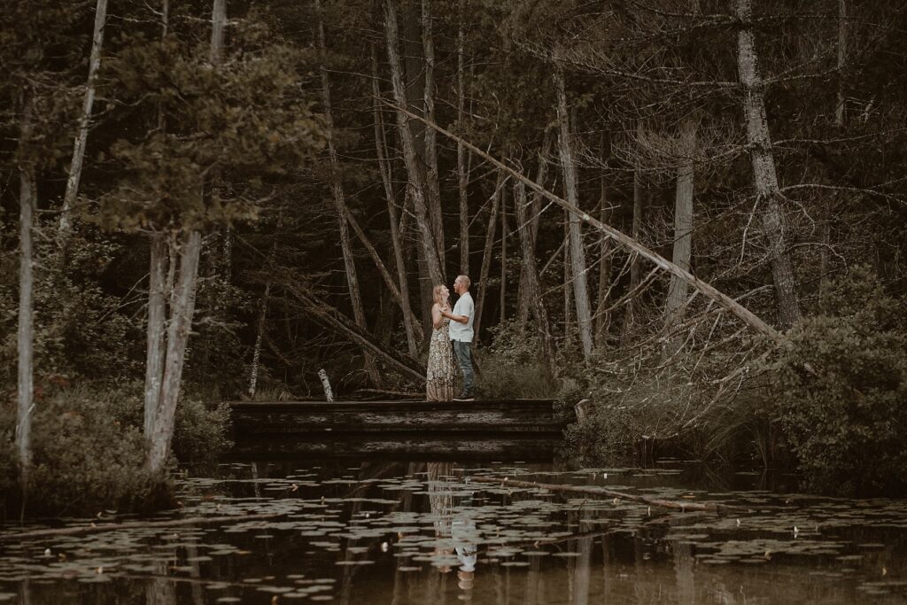 Couple dancing together on a dock in nature.