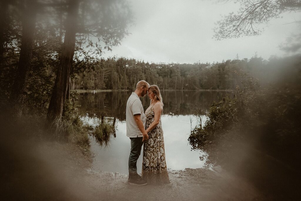 Couple standing together in front of a dream-like lake.