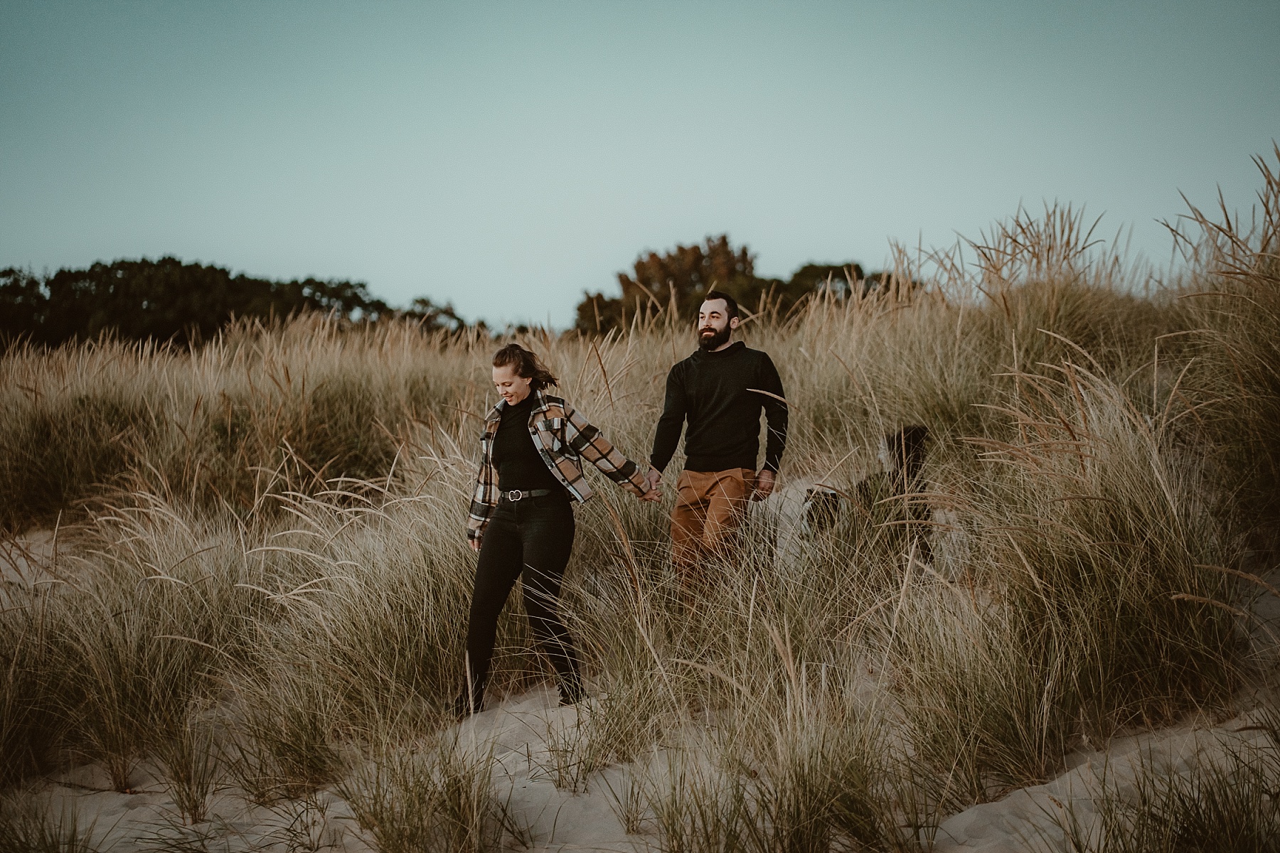 Couple walking down a small sand dune with Border Collie in Frankfort, MI