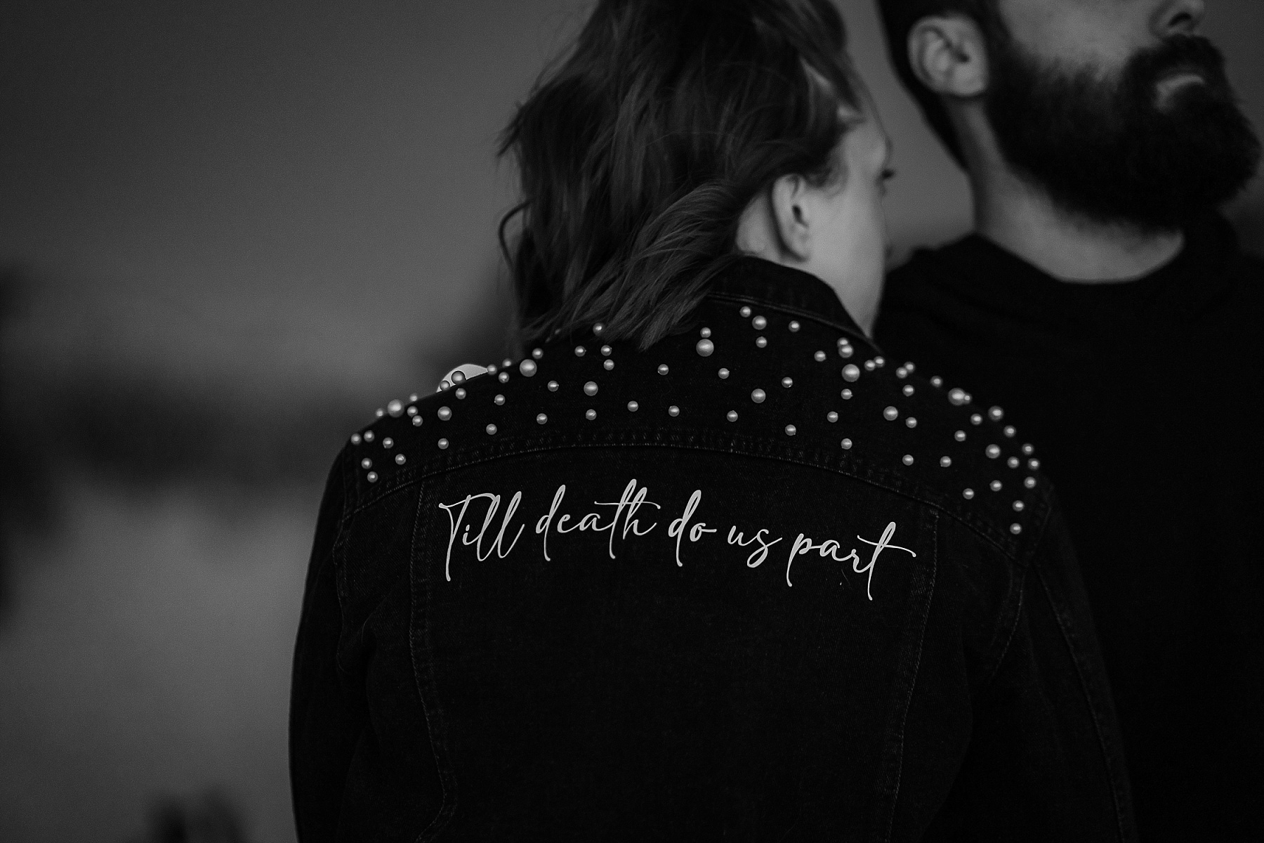 Close up of jean jacket that says Till Death Do Us Part on the back in black and white.