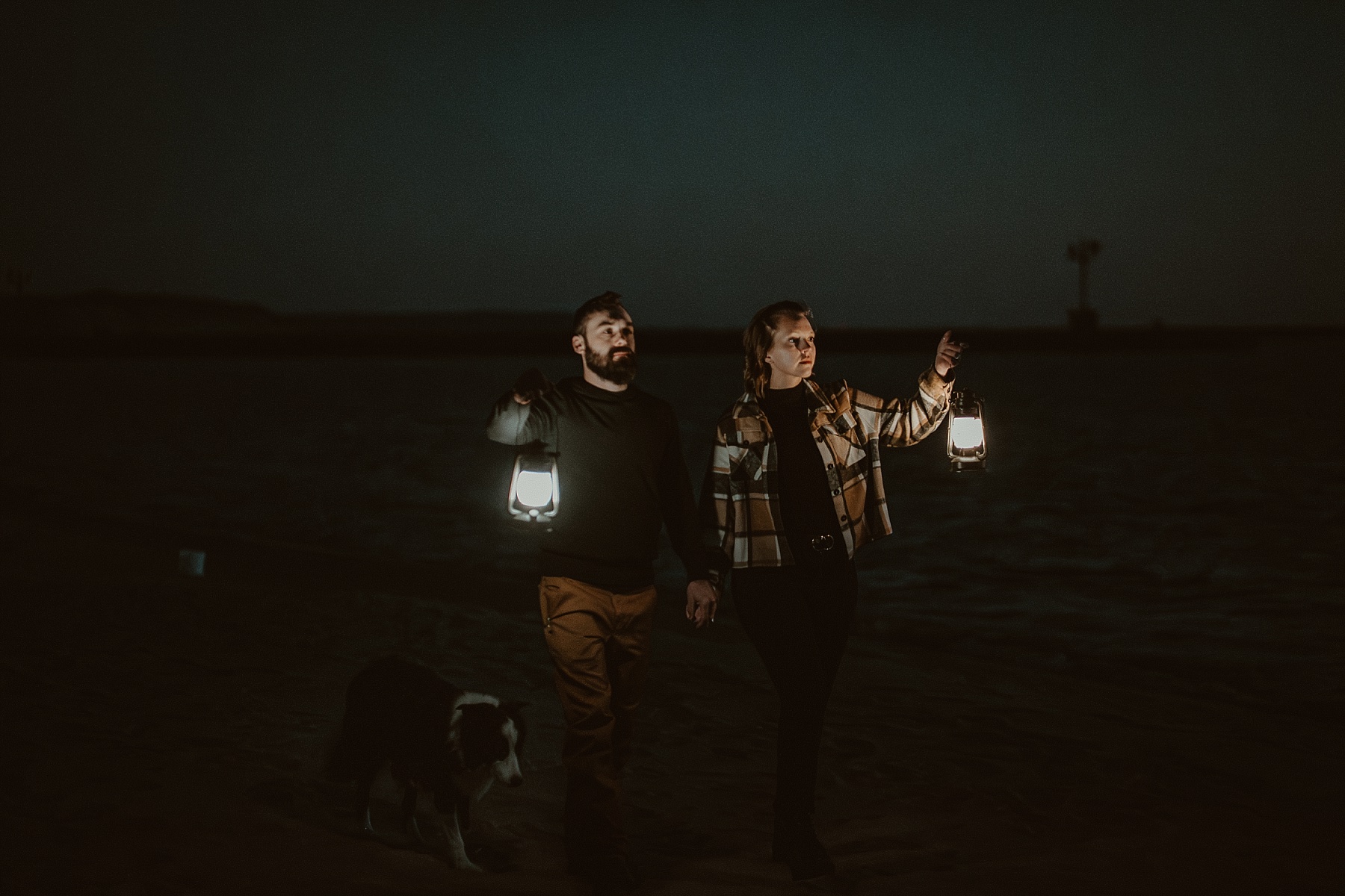 Couple holding hands carrying lanterns at blue hour on Lake Michigan.