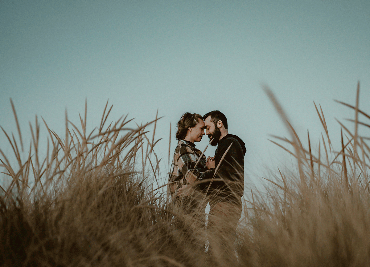 GIF of couple holding each other at top of small sand dune at engagement session on Lake Michigan.
