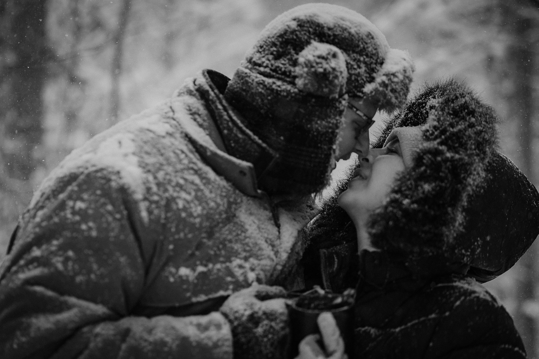 Romantic black & white winter engagement photos in Hartwick Pines State Park during a snowstorm.