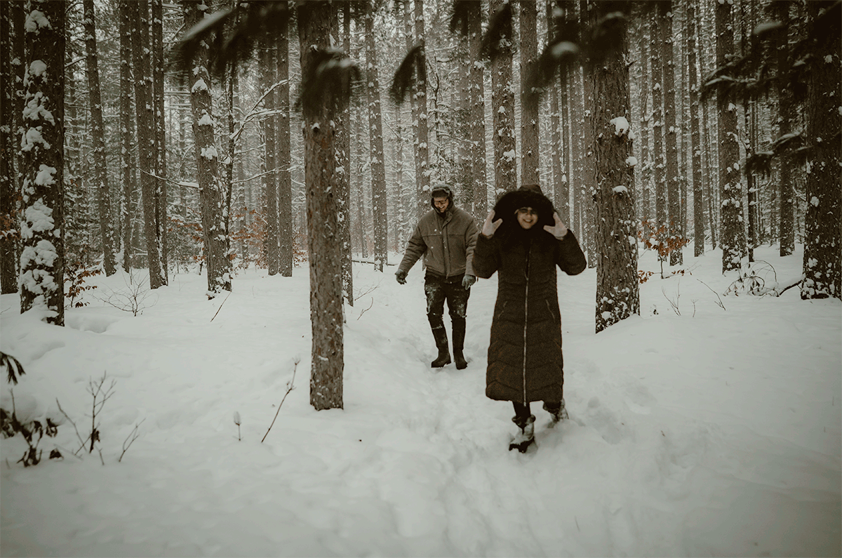 GIF of couple having a snowball fight in heavy snowfall during winter engagement session at Hartwick Pines State Park in Grayling Michigan.